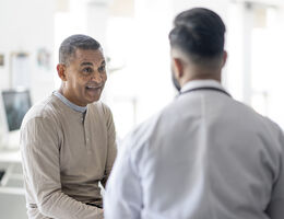 An older man talks to a doctor.