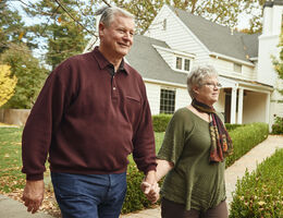 A man and woman hold hands as they walk.